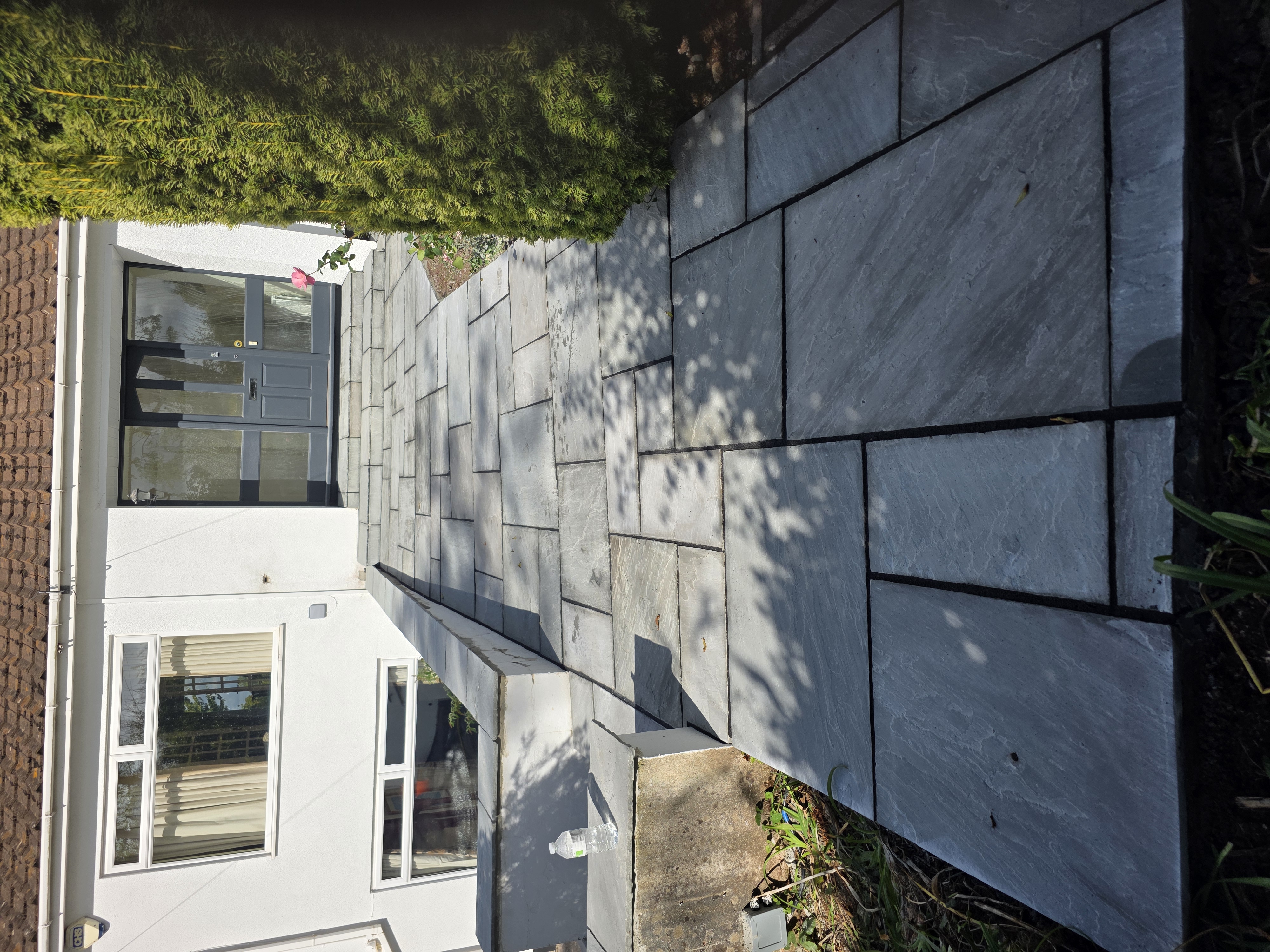 Grey paved entrance path with matching steps leading to a front door